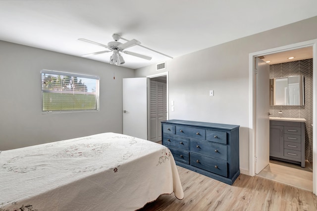 bedroom with a closet, ceiling fan, light wood-type flooring, and ensuite bath