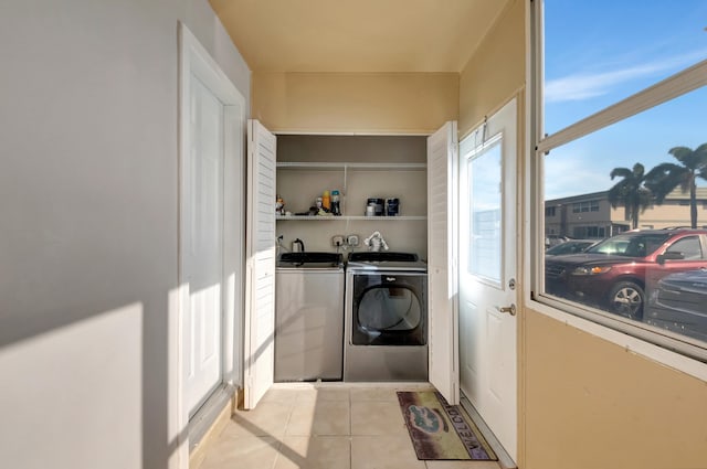 laundry area with independent washer and dryer and light tile patterned floors