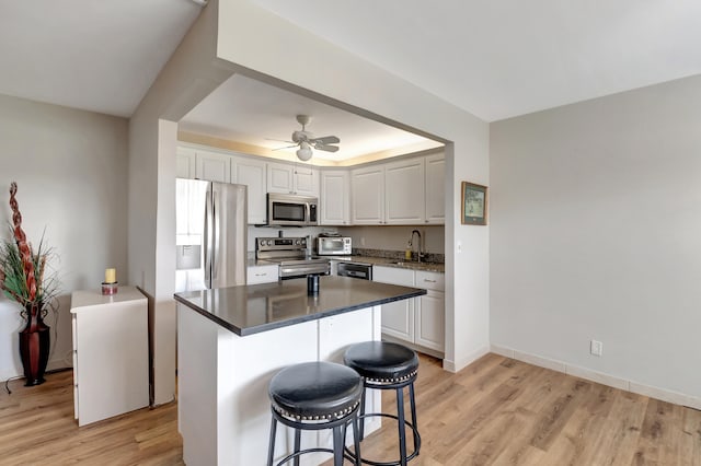 kitchen featuring white cabinetry, a kitchen bar, stainless steel appliances, and light wood-type flooring