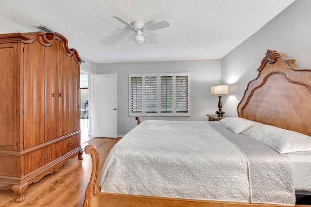 bedroom with light hardwood / wood-style flooring, a textured ceiling, and ceiling fan