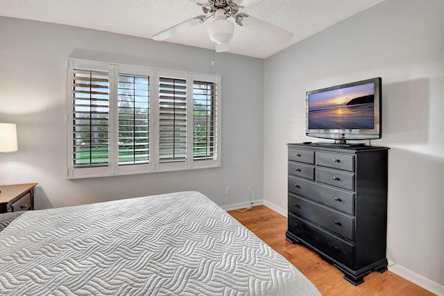 bedroom featuring ceiling fan, a textured ceiling, and light wood-type flooring