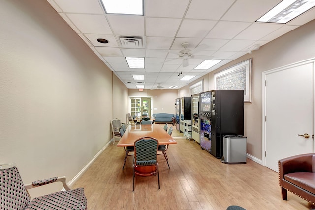 dining area with a drop ceiling, light hardwood / wood-style flooring, and ceiling fan