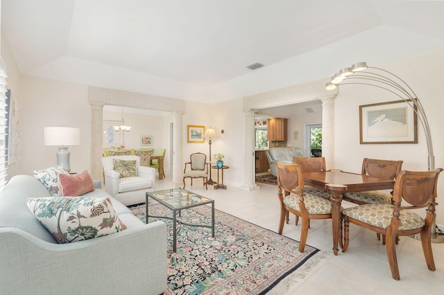 tiled living room featuring a chandelier and ornate columns