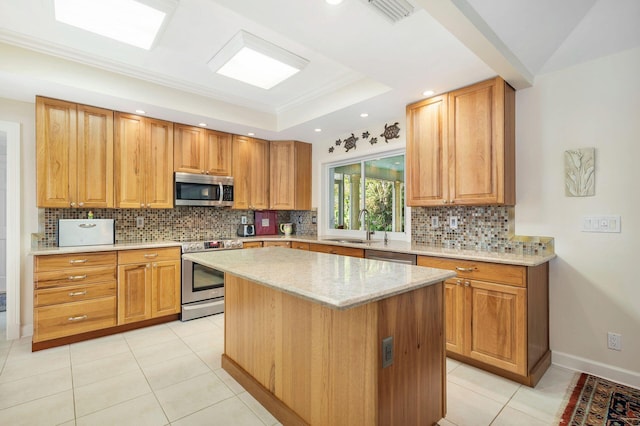 kitchen featuring light stone counters, backsplash, stainless steel appliances, sink, and a center island