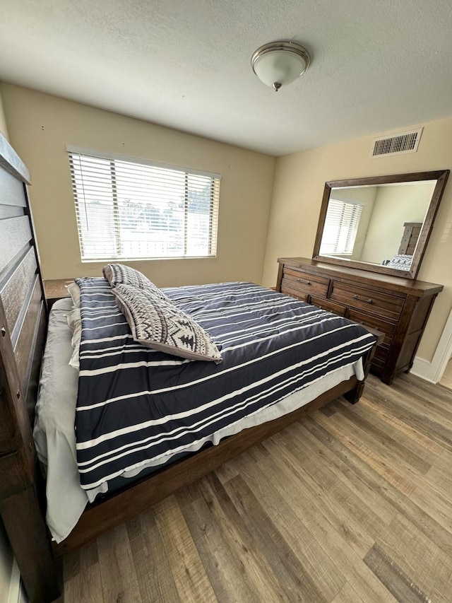 bedroom with a textured ceiling and light hardwood / wood-style floors