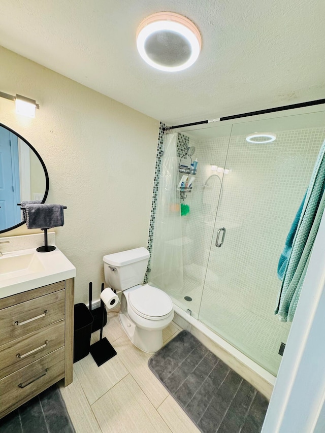 bathroom with a textured ceiling, toilet, vanity, an enclosed shower, and tile patterned flooring