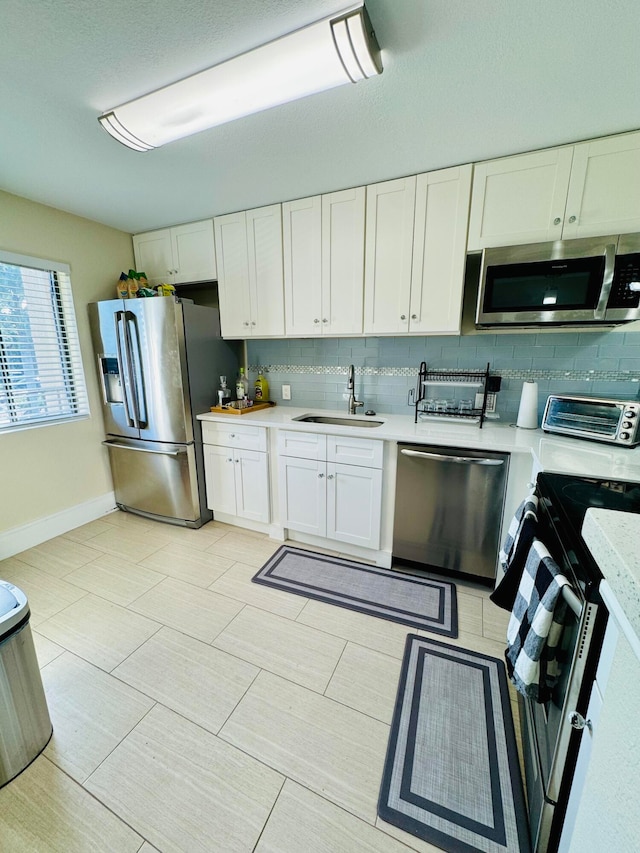 kitchen featuring white cabinetry, stainless steel appliances, sink, and backsplash