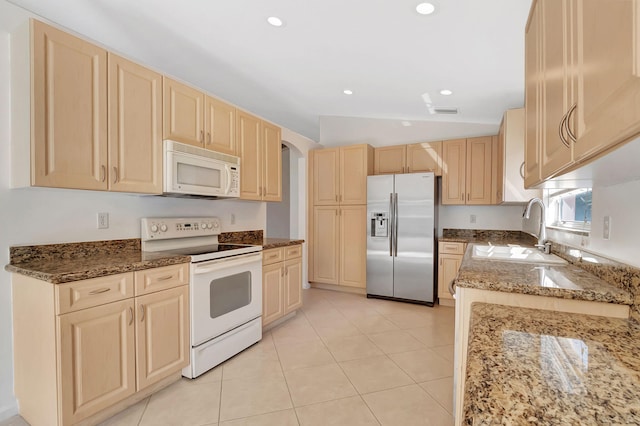 kitchen featuring lofted ceiling, sink, light stone countertops, light brown cabinetry, and white appliances