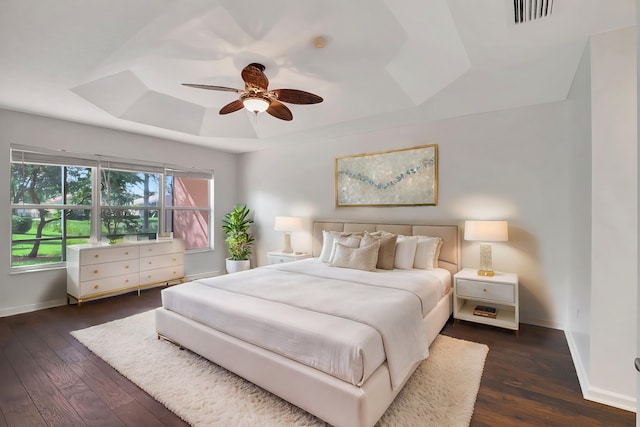 bedroom with a raised ceiling, dark hardwood / wood-style floors, and ceiling fan