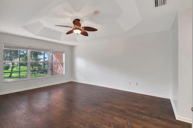 unfurnished room featuring a tray ceiling, a ceiling fan, visible vents, baseboards, and hardwood / wood-style flooring