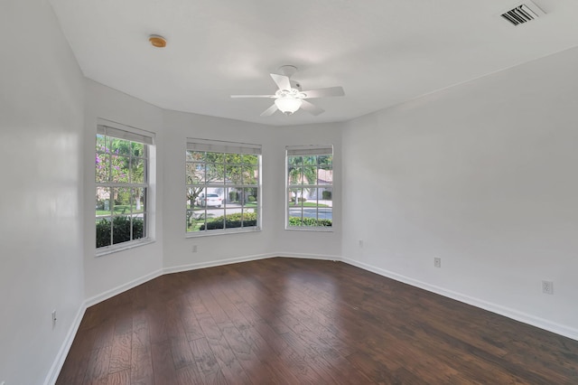 unfurnished room featuring a ceiling fan, visible vents, baseboards, and dark wood-type flooring