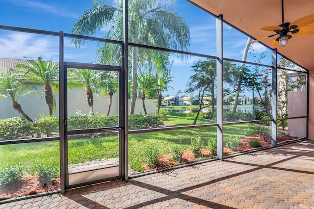 unfurnished sunroom with a ceiling fan and a water view