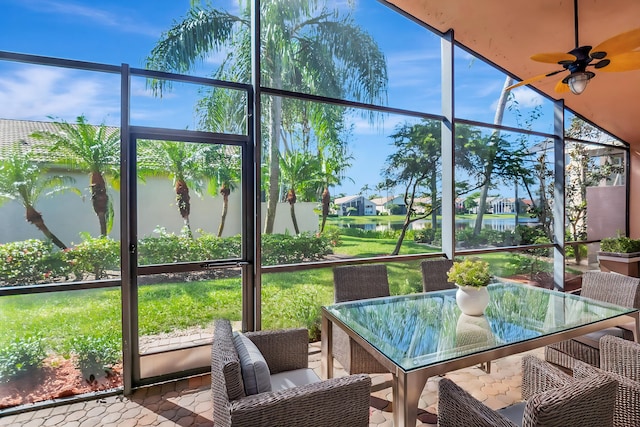 sunroom / solarium with outdoor dining space, a ceiling fan, and a water view