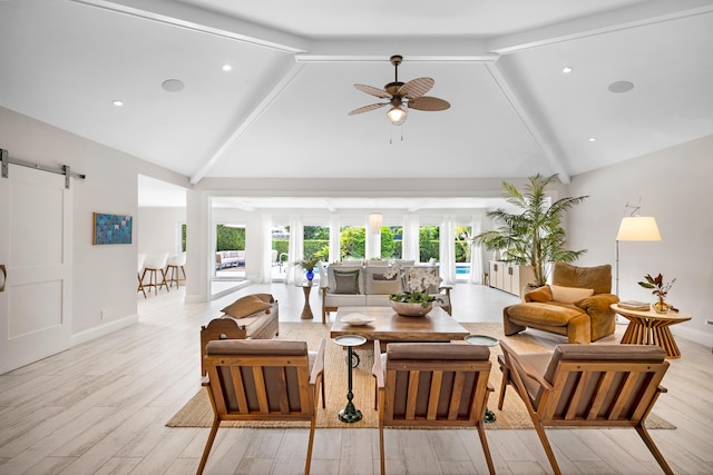 living room featuring ceiling fan, beam ceiling, light wood-type flooring, and a barn door