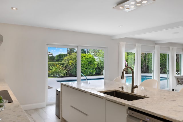 kitchen featuring white cabinets, light stone countertops, light hardwood / wood-style flooring, dishwasher, and sink