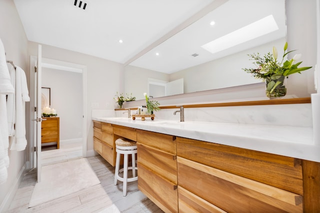 bathroom with vanity, hardwood / wood-style floors, and a skylight