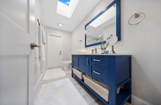 bathroom with vanity, a shower, toilet, and a skylight