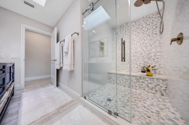 bathroom featuring a skylight and an enclosed shower