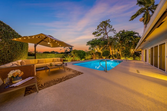 pool at dusk with a patio area and outdoor lounge area