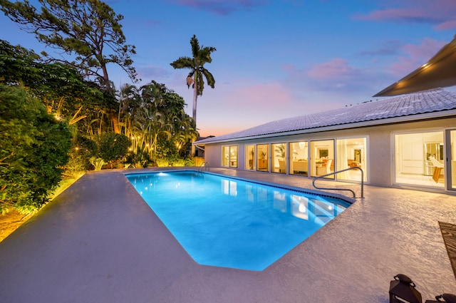 pool at dusk with a patio area