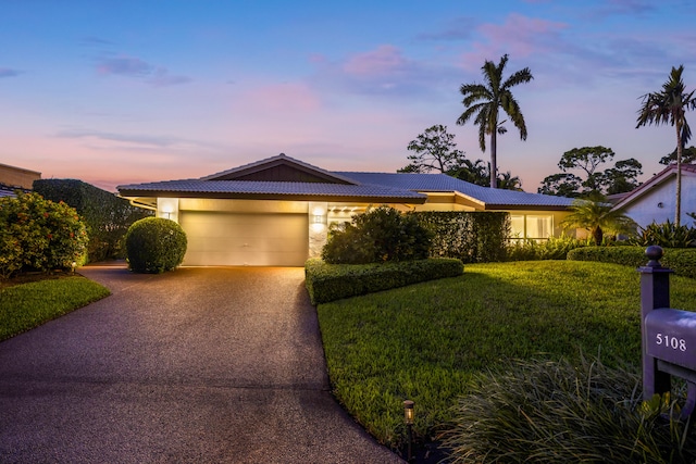 single story home featuring a garage and a lawn