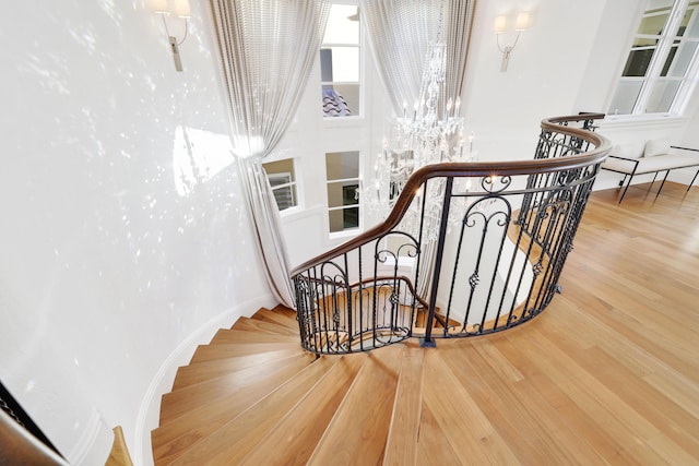 stairs featuring hardwood / wood-style flooring and an inviting chandelier