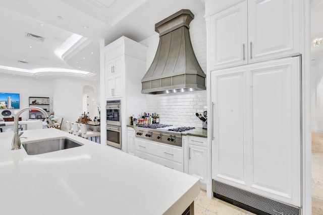 kitchen featuring sink, appliances with stainless steel finishes, custom range hood, and white cabinetry