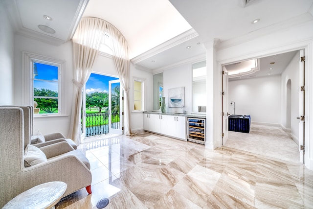 interior space with crown molding, white cabinets, and beverage cooler