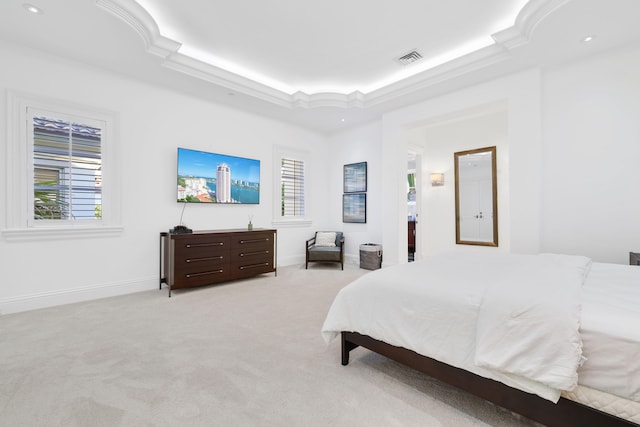 bedroom with ornamental molding, light carpet, and a raised ceiling