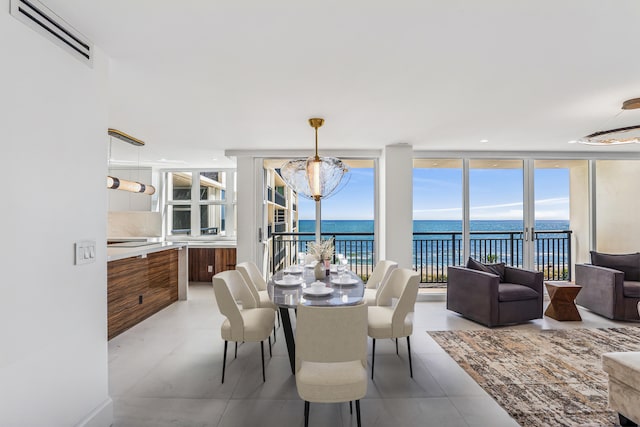 tiled dining space with an AC wall unit, a chandelier, a water view, and floor to ceiling windows