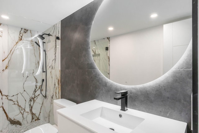 bathroom featuring tile walls, tiled shower, vanity, and toilet