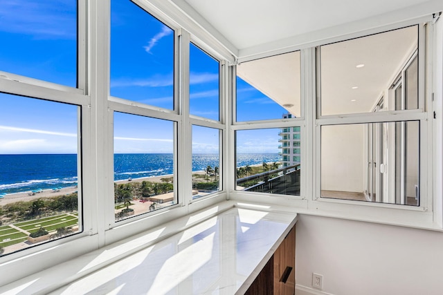 interior space featuring a beach view, a water view, and a healthy amount of sunlight