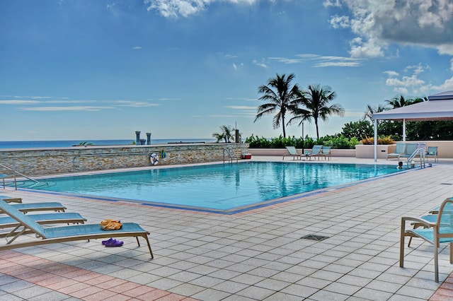 view of swimming pool featuring a patio and a water view