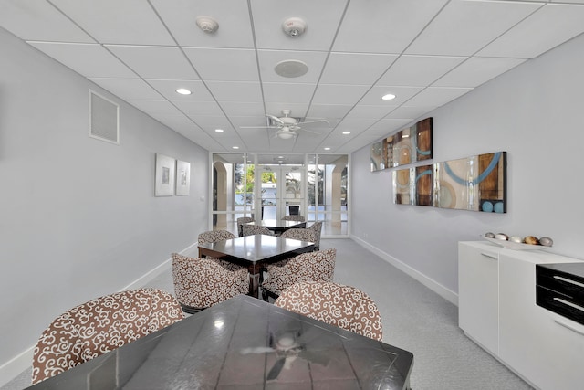 carpeted dining area with french doors, a paneled ceiling, and ceiling fan