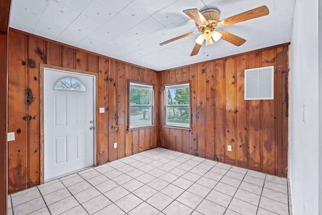 foyer featuring wooden walls, light tile patterned flooring, and ceiling fan