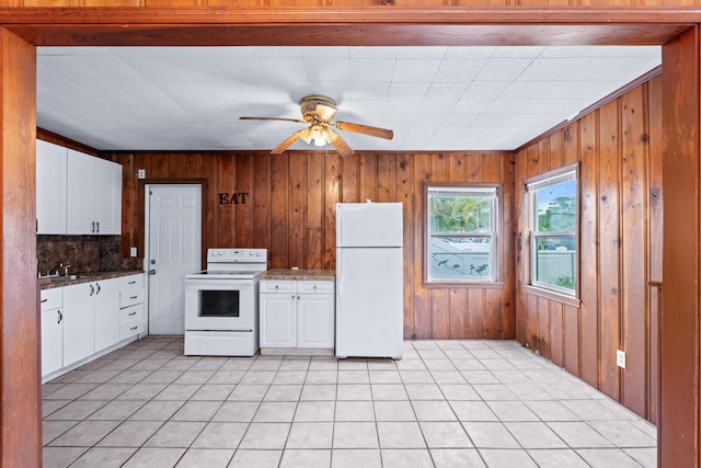 kitchen featuring white appliances, wood walls, backsplash, ceiling fan, and white cabinets