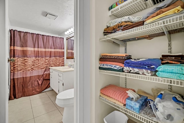 bathroom with tile patterned flooring, vanity, a textured ceiling, and toilet