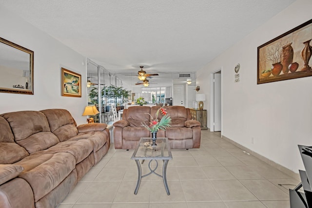 living room featuring a textured ceiling, light tile patterned floors, and ceiling fan