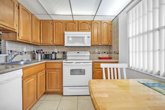 kitchen featuring sink, a drop ceiling, tasteful backsplash, light tile patterned floors, and white appliances