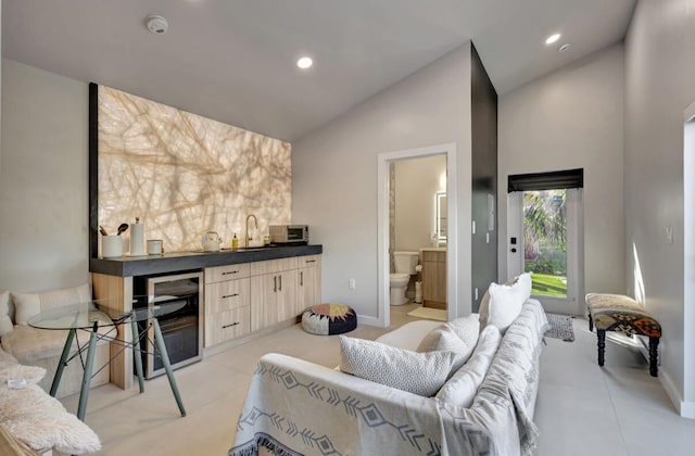 living room featuring wet bar, high vaulted ceiling, light tile patterned floors, and beverage cooler