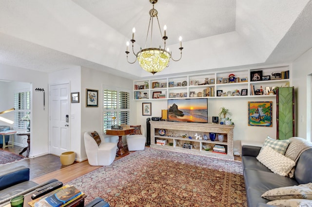 living room with a raised ceiling, wood-type flooring, a textured ceiling, and a notable chandelier