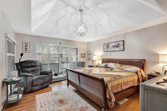 bedroom featuring a textured ceiling, light hardwood / wood-style floors, and a notable chandelier