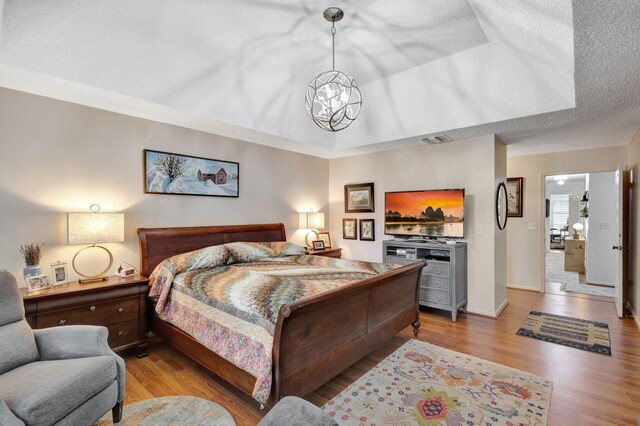 bedroom featuring a chandelier, a textured ceiling, and light hardwood / wood-style floors