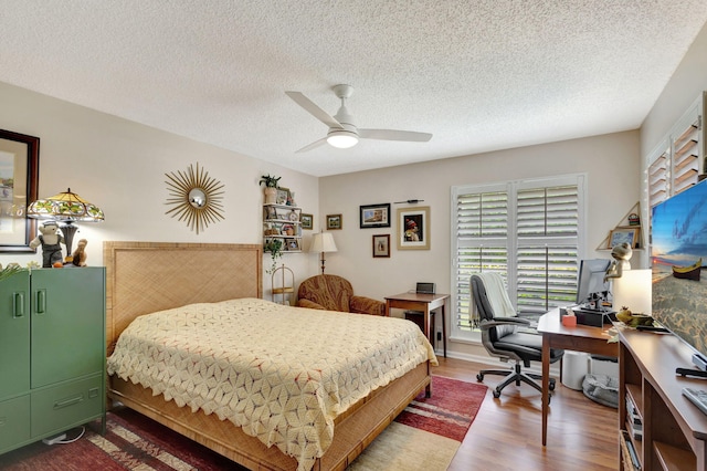 bedroom with hardwood / wood-style floors, a textured ceiling, and ceiling fan