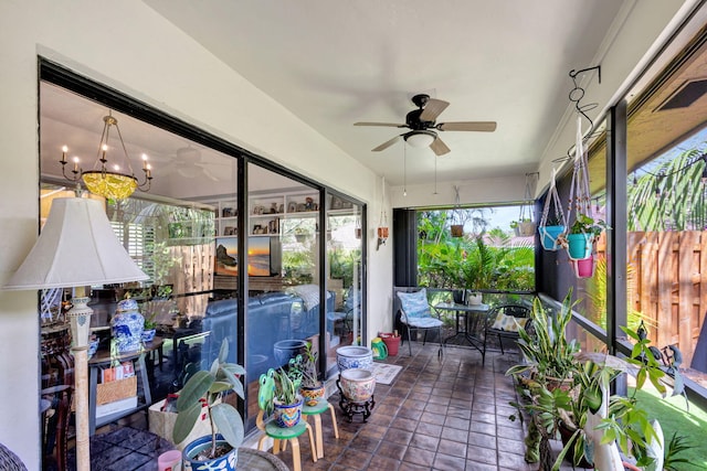 sunroom featuring ceiling fan with notable chandelier