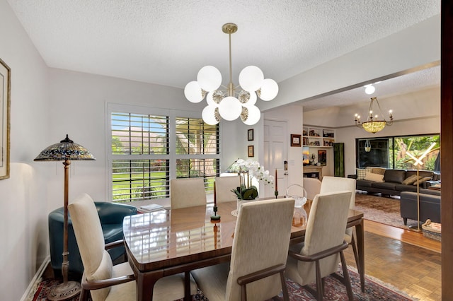 dining area with parquet flooring, a textured ceiling, and an inviting chandelier