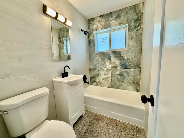 full bathroom with tiled shower / bath, vanity, toilet, and tile walls