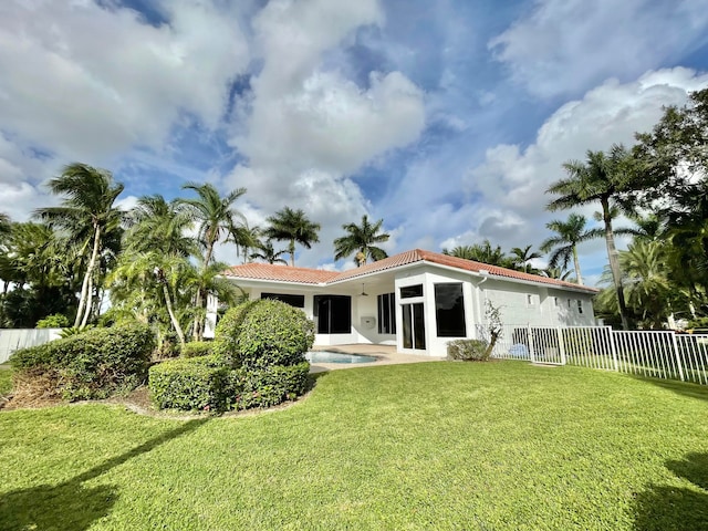 rear view of house featuring a fenced in pool and a lawn