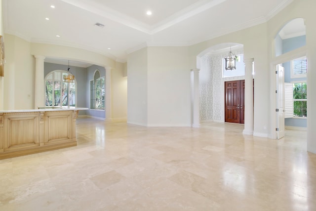 foyer entrance with decorative columns, crown molding, and a chandelier