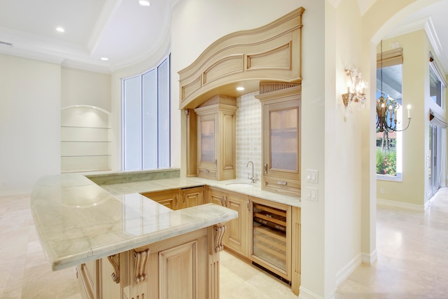 bar with light brown cabinetry, beverage cooler, crown molding, sink, and a notable chandelier